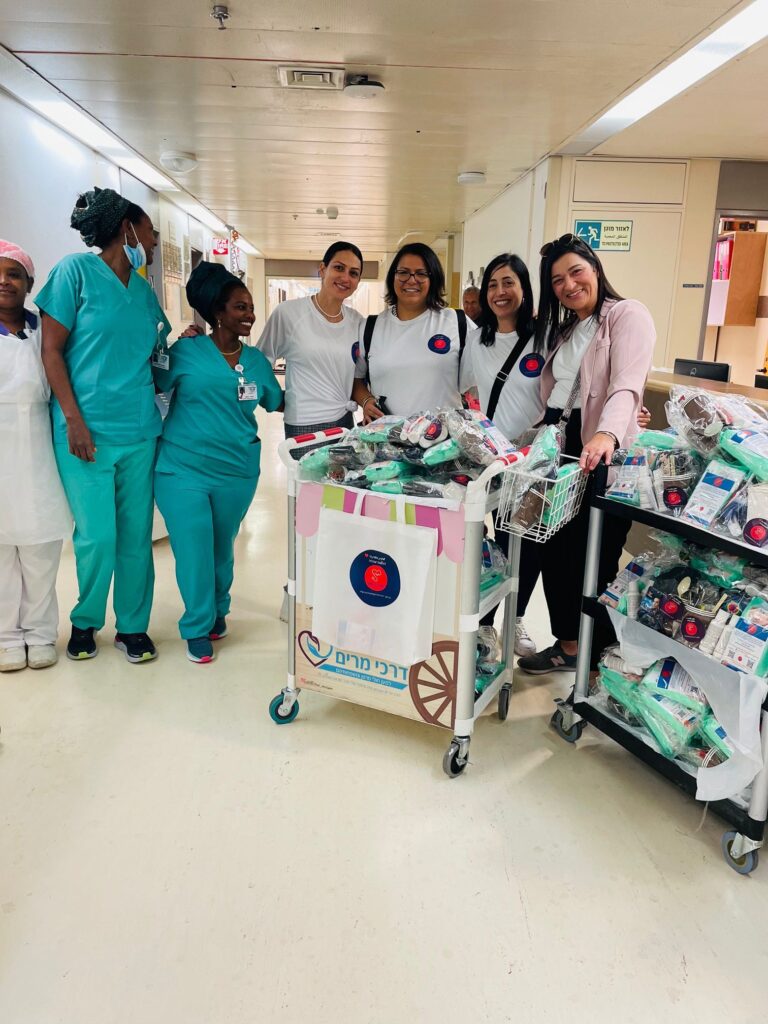 Group of women smiling next to hospital staff with packages