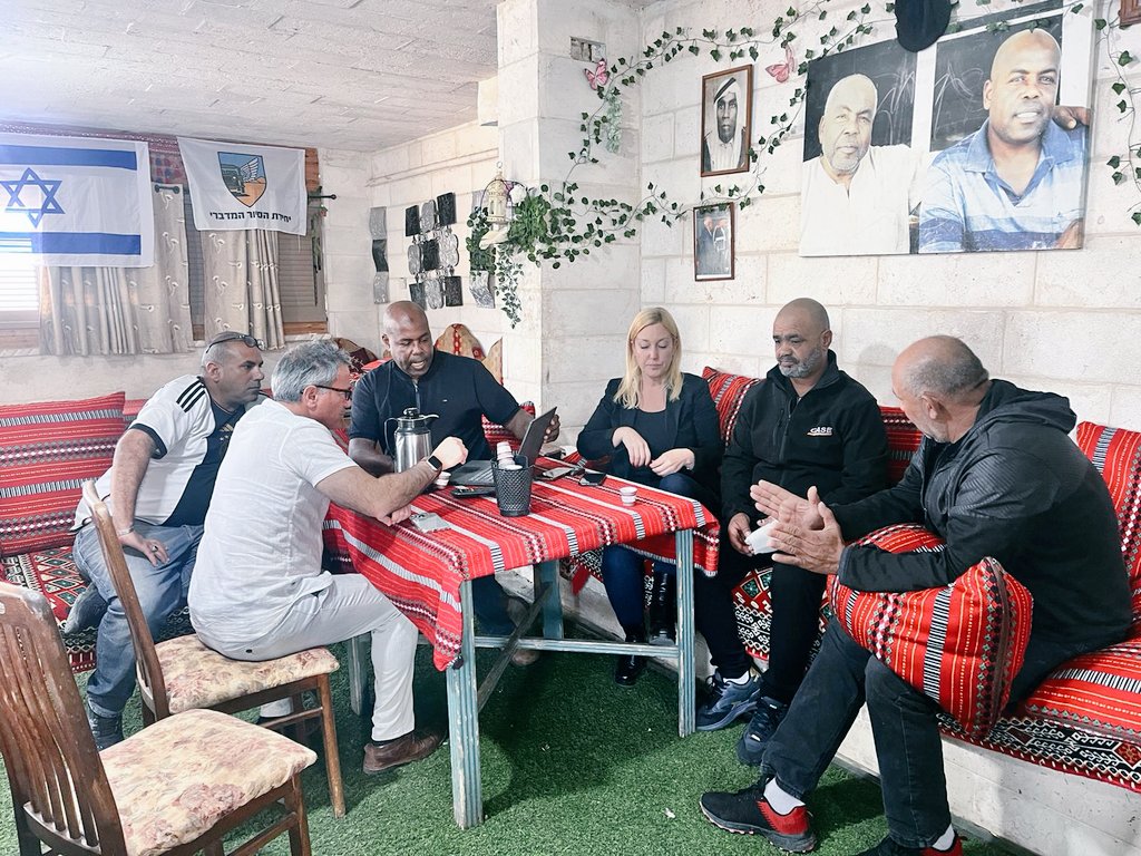 Group of adults seated around a table, in conversation